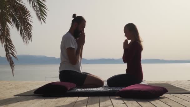 Profesora de masaje de yoga pone las manos en namaste y abraza al estudiante en el lugar costero — Vídeos de Stock