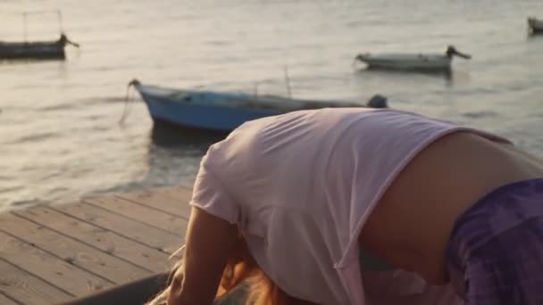 Blondýny žena praxe jóga v přímořském hotelu salonek zóny při východu slunce — Stock video