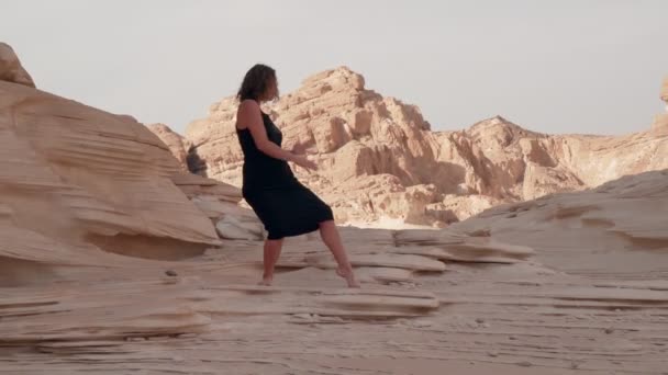 Hermosa chica caucásica en vestido negro práctica de baile extático en el desierto — Vídeo de stock