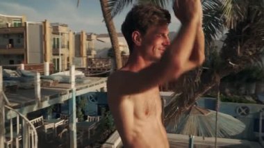 Güneş doğarken deniz kıyısında yoga yapan zayıf beyaz bir adam.