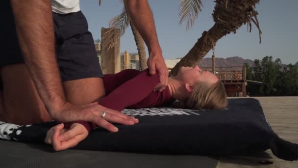 Masseur man gör en thai yoga massage för ung flicka på stranden vid solnedgången — Stockvideo
