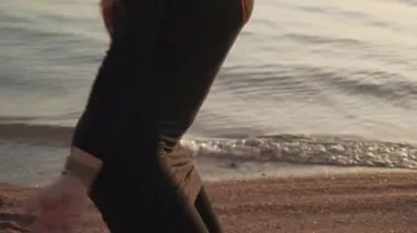 Siyah takım elbiseli kızıl kız gün batımında coşkulu bir şekilde dans ediyor.