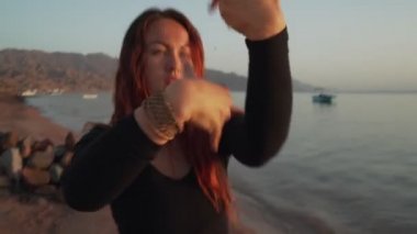 Kızıl saçlı kız gün batımında coşkulu dans alıştırması yapıyor. Dinamik aktif kamera hareketi