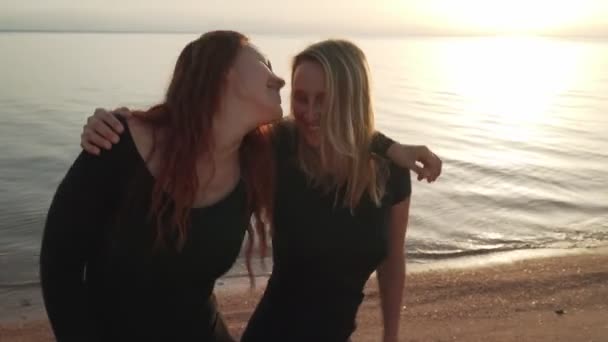 Divertenti ragazze caucasiche in abito nero che ballano in riva al mare sotto il sole — Video Stock