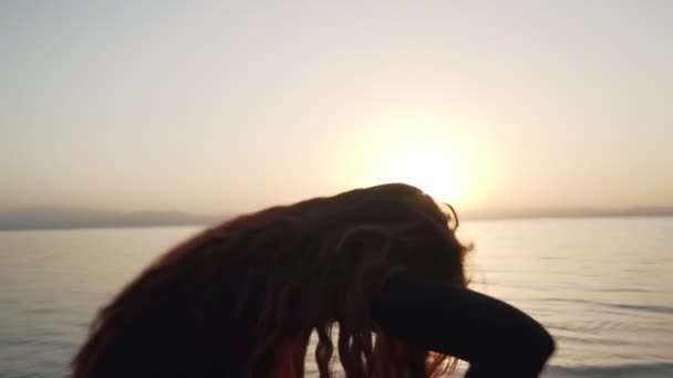 Hermosa pelirroja práctica de baile extático en la costa del mar al atardecer — Vídeo de stock