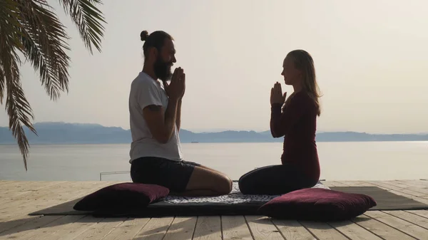 Yoga öğretmeni deniz kenarındaki bir yerde öğrenciyle el ele verdi..