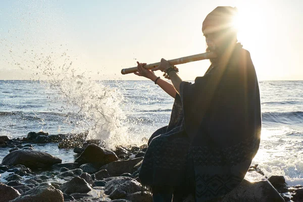 ชายที่เล่นเครื่องดนตรีอินเดียแบนซูรี ในแสงแดดที่ชายฝั่งทะเล รูปภาพสต็อกที่ปลอดค่าลิขสิทธิ์