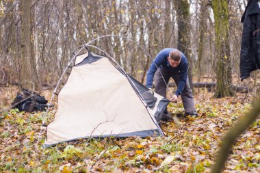 Genç adam ormanda bir çadır koyarak