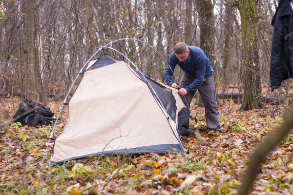 Ung man sätta ett tält i skogen — Stockfoto