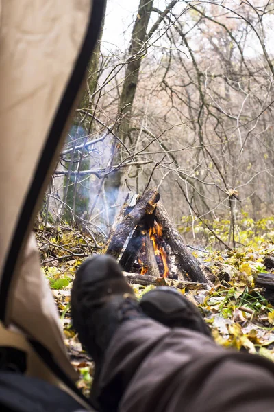 Toeristische in de tent liggen en kijken naar de brand in de bergbos — Stockfoto