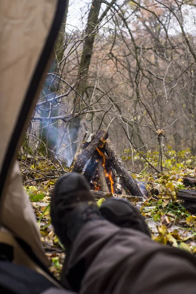 Toeristische in de tent liggen en kijken naar de brand in de bergbos — Stockfoto