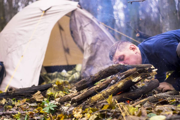 Toeristische wakkeren het vuur in de achtergrond-tent — Stockfoto