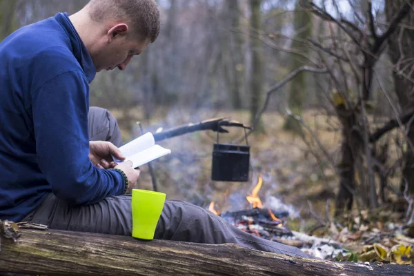 Tourist liest ein Buch und trinkt Tee in einem ruhigen Herbstwald — Stockfoto