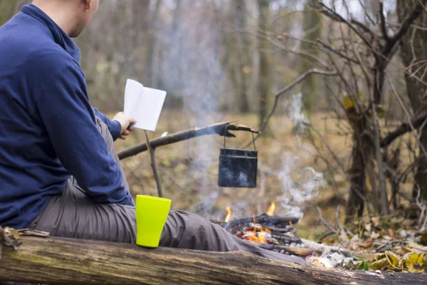 Турист читає книгу і п'є чай в тихому осінньому лісі — стокове фото
