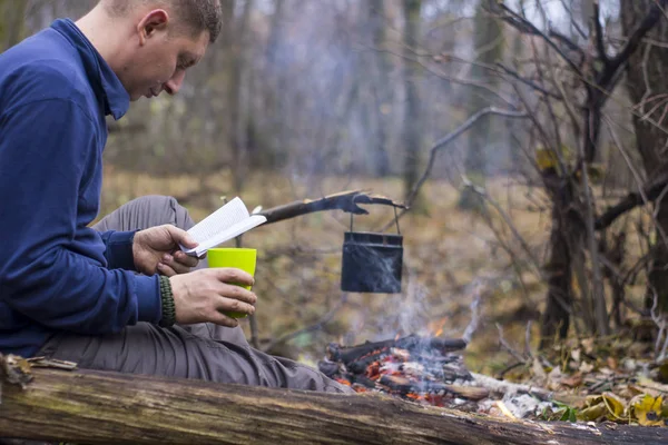 Toeristische lezen van een boek en het drinken van thee in een rustige herfst bos — Stockfoto