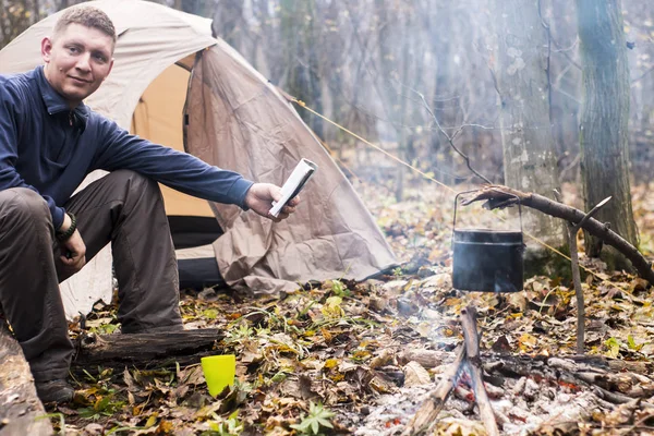 Турист читає книгу і п'є чай в тихому осінньому лісі — стокове фото