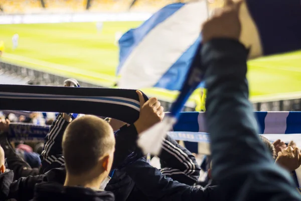 Fans in the stadium holding flags of their football team — Stock Photo, Image