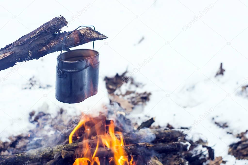 winter forest, the tourist warm tea in a pot