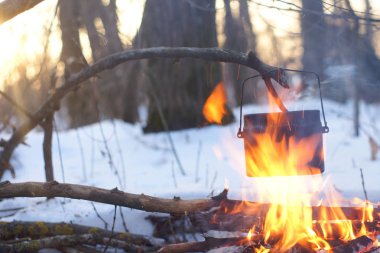 Kış ormanda ateş üzerinde kaynar su bir sürahi sıcak,
