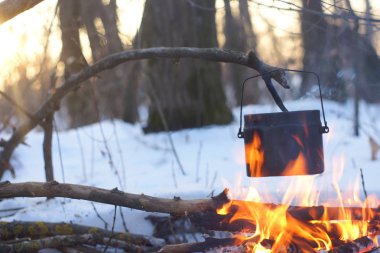 Kış ormanda ateş üzerinde kaynar su bir sürahi sıcak,