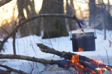 Kış ormanda ateş üzerinde kaynar su bir sürahi sıcak,