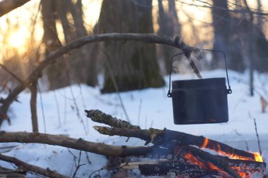 Kış ormanda ateş üzerinde kaynar su bir sürahi sıcak,