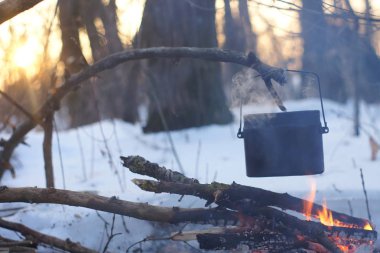 Kış ormanda ateş üzerinde kaynar su bir sürahi sıcak,