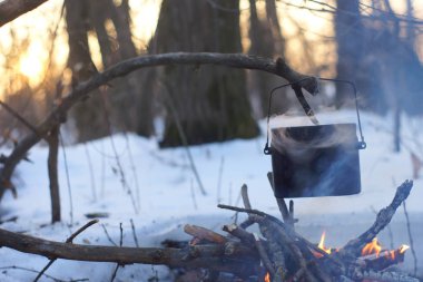 Kış ormanda ateş üzerinde kaynar su bir sürahi sıcak,
