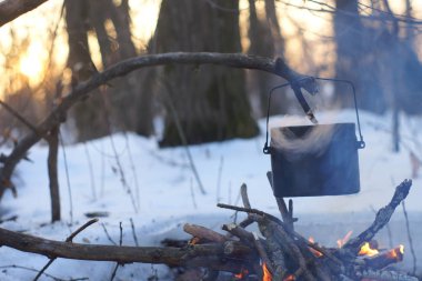 Kış ormanda ateş üzerinde kaynar su bir sürahi sıcak,