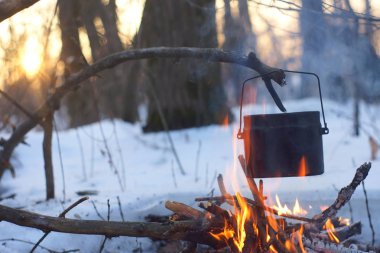 Kış ormanda ateş üzerinde kaynar su bir sürahi sıcak,