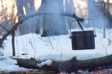 Kış ormanda ateş üzerinde kaynar su bir sürahi sıcak,