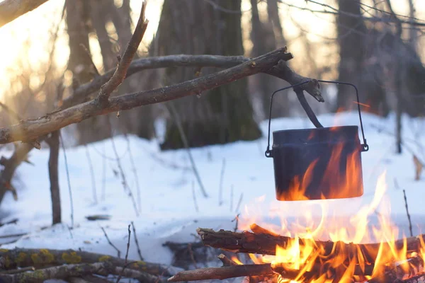 Kış ormanda ateş üzerinde kaynar su bir sürahi sıcak,