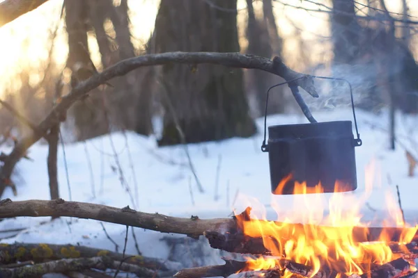 Kış ormanda ateş üzerinde kaynar su bir sürahi sıcak,