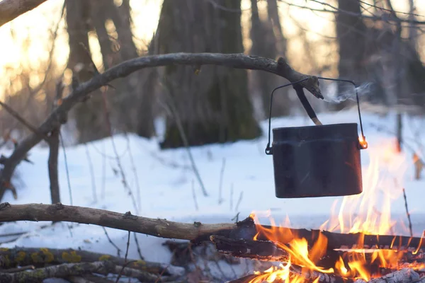 Kış ormanda ateş üzerinde kaynar su bir sürahi sıcak,