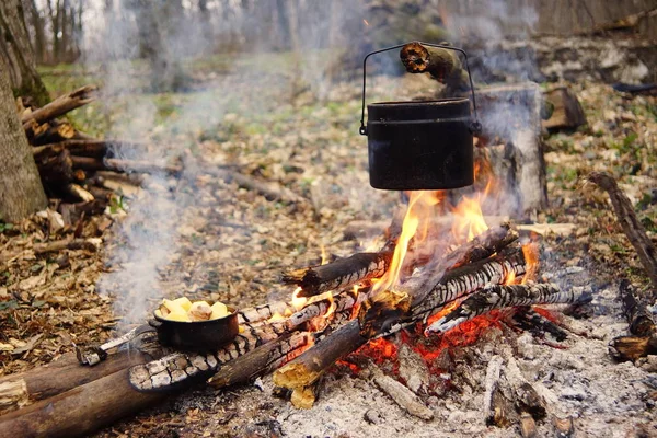 Hervidor turístico en el fuego del campamento con tienda de campaña en el fondo. mano con palo sobre fire.a —  Fotos de Stock