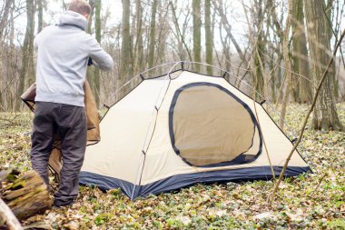 Genç adam ormanda bir çadır koyarak bir