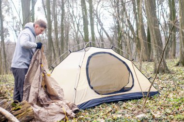 Genç adam ormanda bir çadır koyarak bir