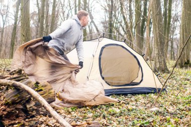 Genç adam ormanda bir çadır koyarak bir