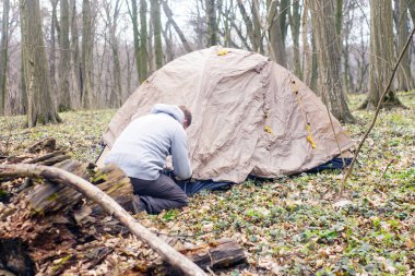 Genç adam ormanda bir çadır koyarak bir