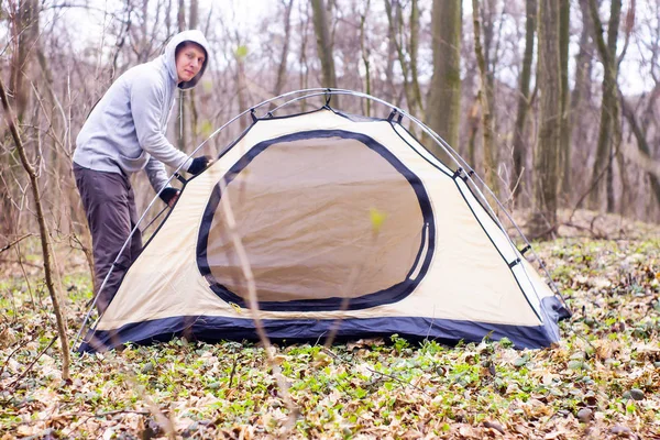 Ung man sätta ett tält i skogen en — Stockfoto