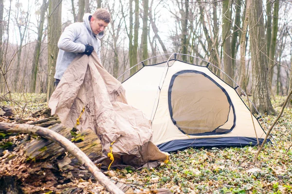 Ung man sätta ett tält i skogen en — Stockfoto