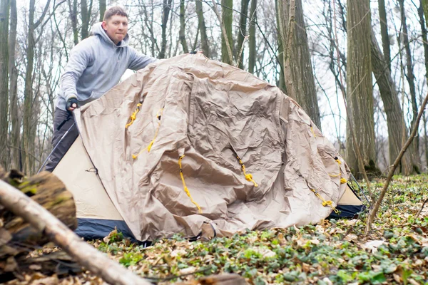 Ung man sätta ett tält i skogen en — Stockfoto