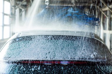 Oto yıkama, siyah arabaya otomatik oto yıkama, kırmızı ve mavi fırça döner. Yıkama araç.