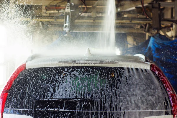 Lavado de autos, coche negro en lavado automático de autos, cepillo rojo y azul giratorio. Vehículo de lavado . — Foto de Stock
