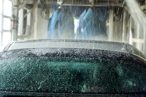 Lavage de voiture, voiture noire en lavage automatique de voiture, brosse rotative rouge et bleue. Véhicule de lavage . — Photo