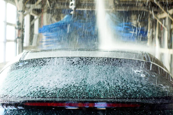 Lavagem de carro, carro preto em lavagem automática de carro, girando escova vermelha e azul. Veículo de lavagem . — Fotografia de Stock