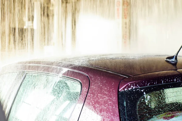 Car wash, black car in automatic car wash, rotating red and blue brush. Washing vehicle. — Stock Photo, Image