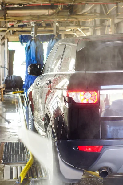 Lavado de autos, coche negro en lavado automático de autos, cepillo rojo y azul giratorio. Vehículo de lavado . — Foto de Stock