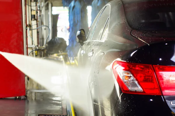 Lavagem de carro, carro preto em lavagem automática de carro, girando escova vermelha e azul. Veículo de lavagem . — Fotografia de Stock