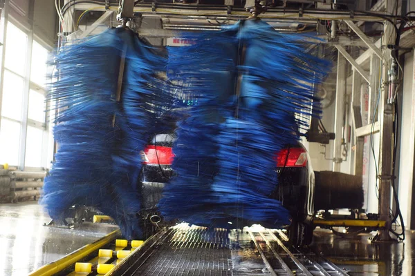 Lavado de autos, coche negro en lavado automático de autos, cepillo rojo y azul giratorio. Vehículo de lavado . — Foto de Stock